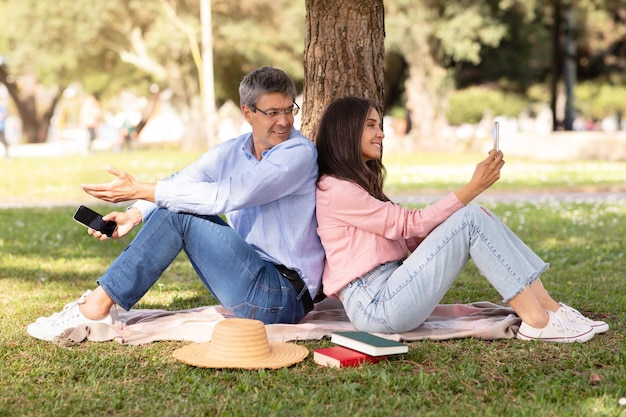 Älteres Paar, das von Social-Media-Sucht abhängig ist, nutzt Smartphones während eines Outdoor-Date im Park