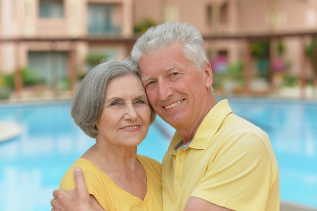 Älteres Paar, das während des Urlaubs am Pool im Resort steht