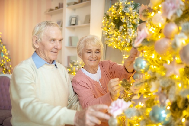 Älteres Paar, das Weihnachtsbaum zusammen verziert