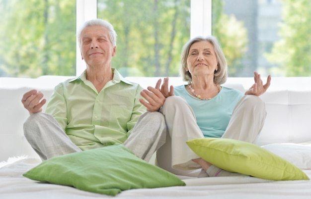 Älteres Paar, das zu Hause mit Augen meditiert