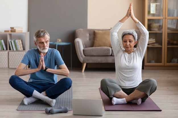 Älteres Paar, das zu Hause Yoga praktiziert