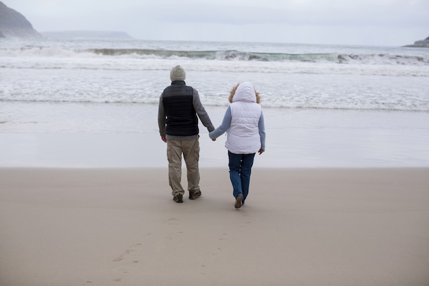 Älteres Paar, das zusammen am Strand geht