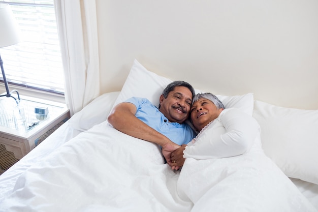 Älteres Paar, das zusammen auf Bett im Schlafzimmer entspannt