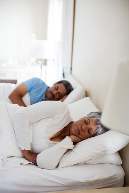 Älteres Paar, das zusammen auf Bett im Schlafzimmer schläft