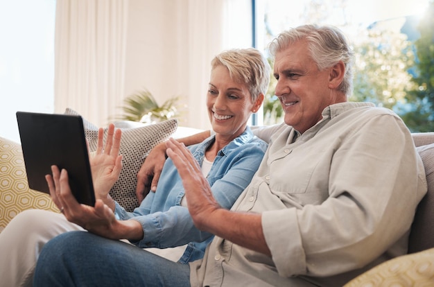 Älteres Paar digitale Tablet-Welle und Videoanruf mit einem Gespräch auf dem Sofa im Wohnzimmer Videokonferenz mit älteren Männern und Frauen lächeln glücklich und unterhalten sich online mit virtuellem Chat