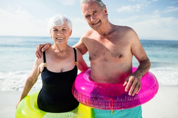 Älteres Paar im aufblasbaren Ring, der am Strand steht