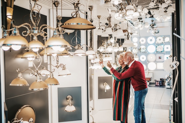Älteres Paar im Hausbeleuchtungsgeschäft, das einen Kronleuchter für ihr Zuhause ausstellt