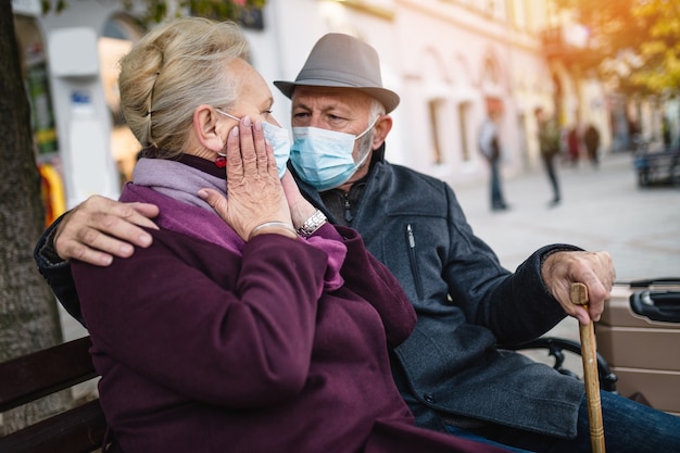 Älteres Paar in Schutzmaske draußen in der Stadt. Luftverschmutzungskonzept.