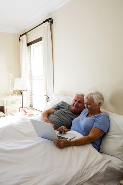 Älteres Paar mit Laptop im Schlafzimmer zu Hause