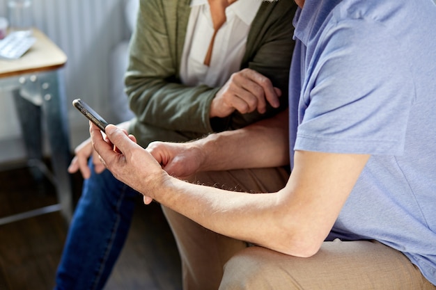 Älteres Paar wird Videoanruf am Telefon mit Familie, Online-Gespräch machen. soziale Distanz, Familie zu Hause, moderne Technologien. Konzentrieren Sie sich auf die Hände