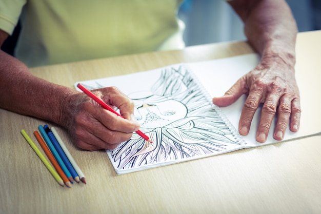 Último homem desenhando com um lápis colorido no livro de desenho