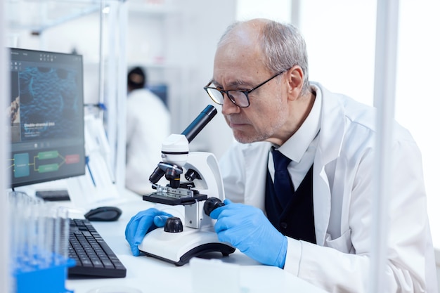 Último homem realizando investigação científica, olhando através do microscópio. Pesquisador químico em laboratório estéril fazendo experimentos para a indústria médica usando tecnologia moderna.