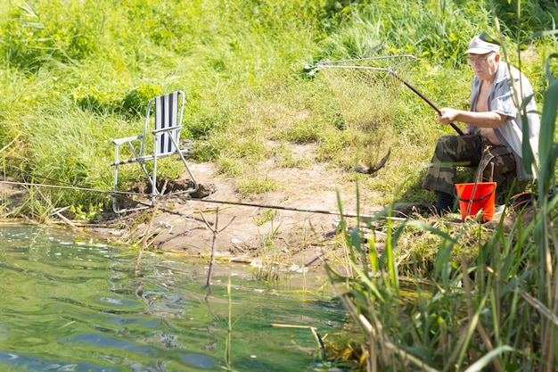 Último homem sentado a pescar à beira de um lago