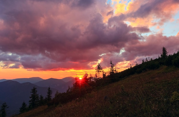 Últimos raios do sol no céu à noite com nuvens. Vista para a montanha do pôr do sol de verão (Cárpatos, Ucrânia).