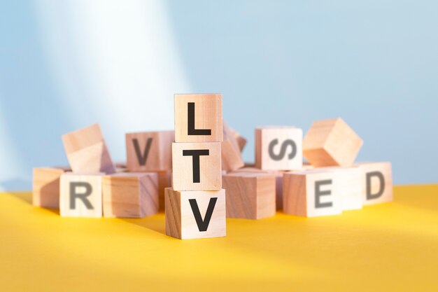 LTV auf Holzwürfeln geschrieben - angeordnet in einer vertikalen Pyramide, grauer und gelber Hintergrund, LTV - kurz für Lifetime Value, Business Concept