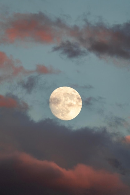 Lua cheia entre as nuvens roxas no crepúsculo