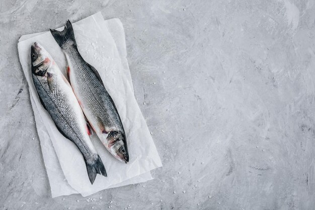 Lubina de pescado crudo fresco con sal marina sobre fondo de piedra gris Vista superior