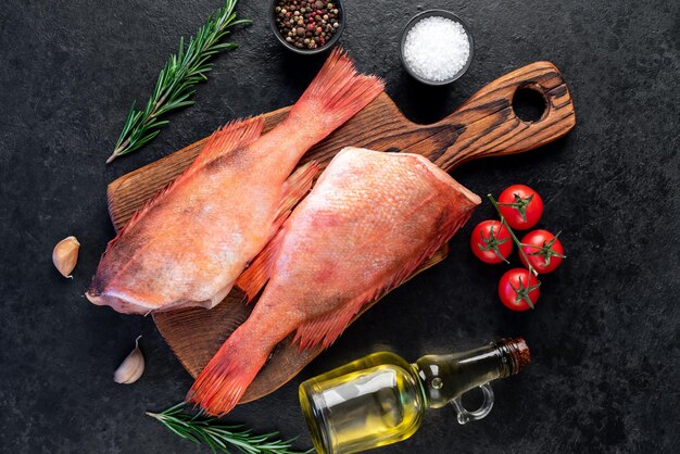 Lubina roja cruda con romero y especias sobre fondo de piedra