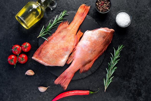 Lubina roja cruda con romero y especias sobre fondo de piedra