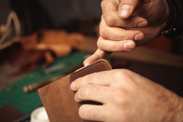 Lubrica los bordes con curtidor de crema hace cartera de cuero negocio artesanal profesional
