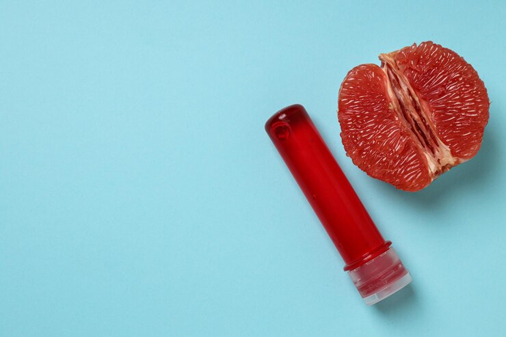 Lubricante con medio pomelo sobre un fondo azul para texto
