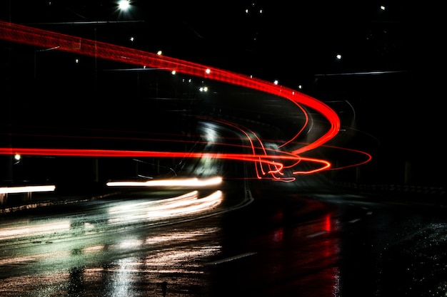 Luces de autos por la noche. Luces de la calle. Ciudad de noche. Carretera nocturna de fotografía de larga exposición. Bandas de luz de colores en la carretera. Camino mojado después de la lluvia.