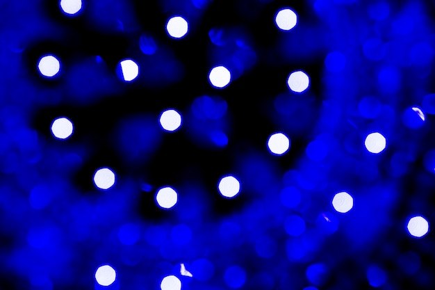 Luces azules abstractas del bokeh de la Navidad aisladas en fondo negro. Árbol de navidad luz ba