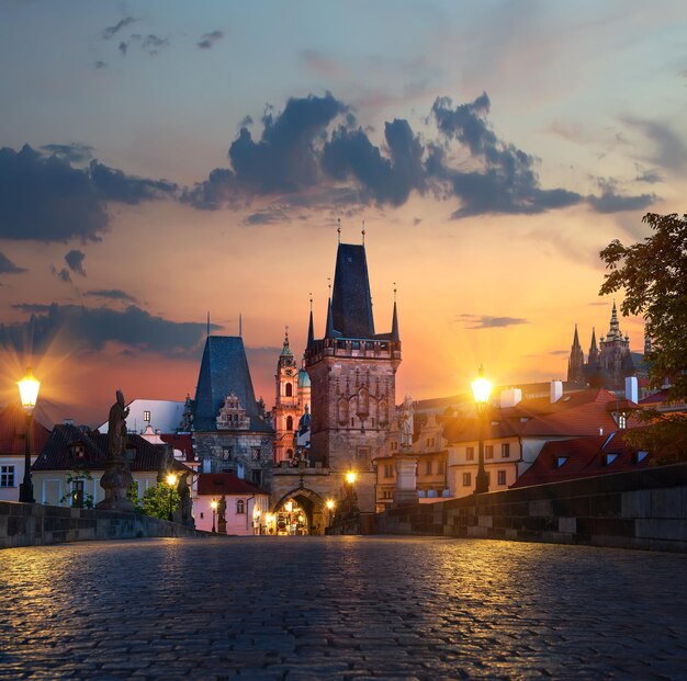 Luces de la calle iluminadas en el Puente de Carlos en Praga al amanecer.