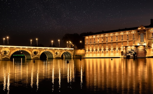 Las luces de la calle se reflejan en el río Garonna y el puente Pont Neuf en Toulouse Francia