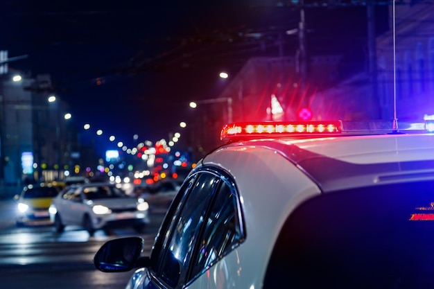 Luces de coches de policía por la noche en la ciudad con enfoque selectivo y tráfico de coches borroso en el bokeh