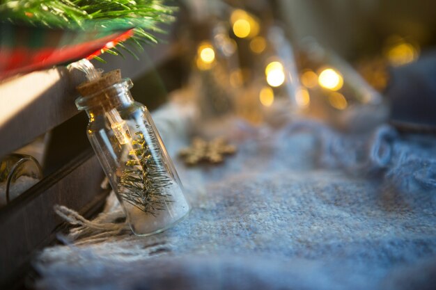 Luces de hadas en un frasco con un árbol de Navidad y primer plano de nieve en un cálido y acogedor plaid con decoración de madera. Navidad y año nuevo, decoración festiva, comodidad en el hogar, preparación para la celebración, estado de ánimo fabuloso