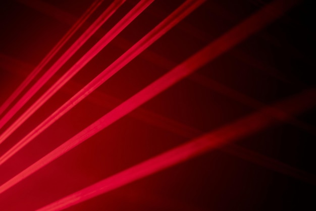 Las luces láser de neón rojo brillante iluminan la oscuridad creando líneas y formas triangulares en efecto de ciencia ficción