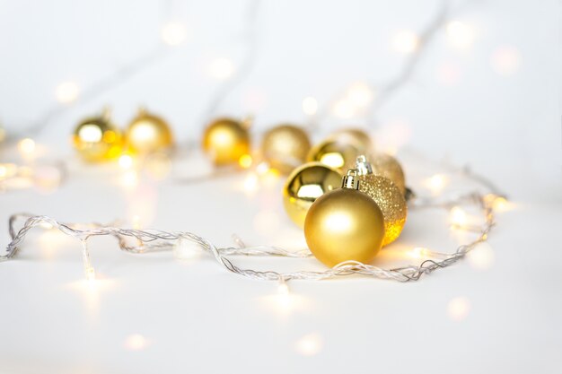 Foto luces de navidad en blanco cálido amarillo en bolas y bolas de navidad doradas sobre fondo claro