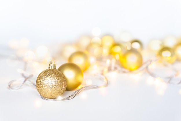 Luces de Navidad en blanco cálido amarillo en bolas y bolas de Navidad doradas sobre fondo claro