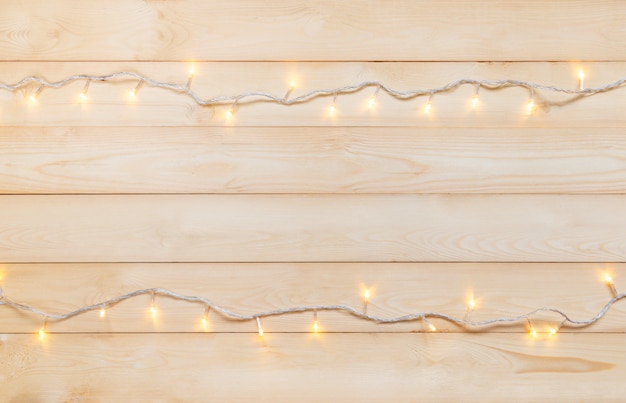 Foto luces de navidad en blanco cálido amarillo sobre una cuerda sobre fondo de madera claro