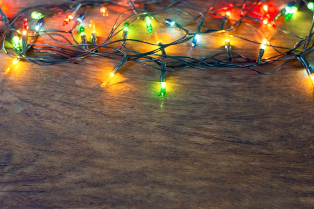 Foto luces de navidad coloridas sobre fondo de madera oscuro