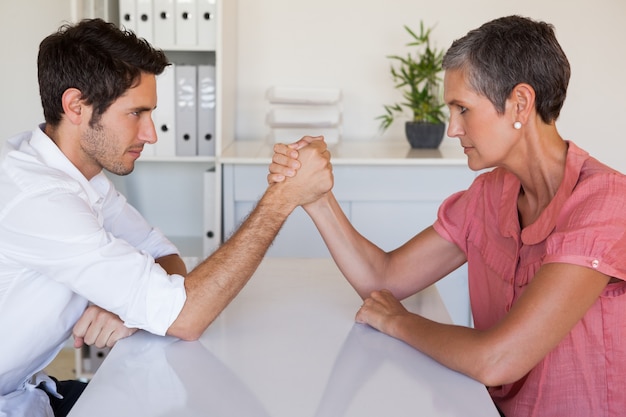 Lucha de brazo de equipo de negocios informal en el escritorio