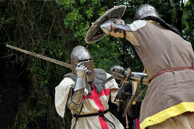 Lucha de caballeros medievales. Caballeros con armadura. Caballeros armados luchando entre los árboles en el bosque.