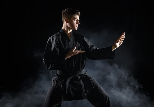 Luchador de karate masculino en kimono negro, postura de combate. Hombre en entrenamiento, artes marciales, competencia de lucha