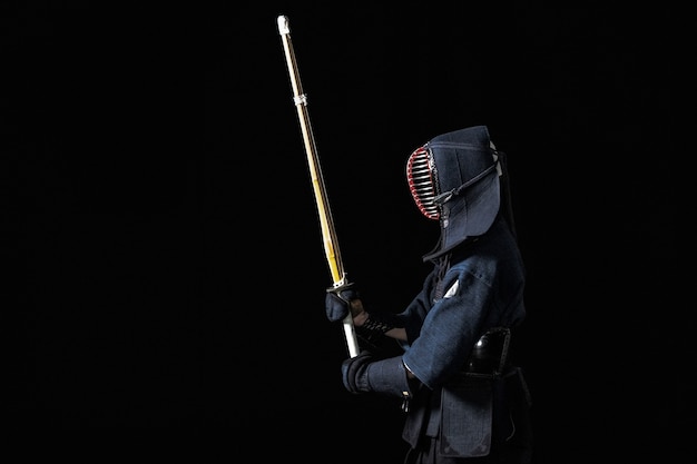 Luchador de kendo con shinai sobre un fondo negro