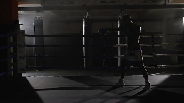 Luchador de kickbox boxeando en la sombra en el ring