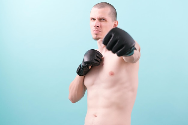 Un luchador de MMA confiado en guantes negros listo para pelear en un fondo azul Postura de lucha Pose Guantes Héroe Potente Resistencia Lucha Combate Conflicto Instrucción Punching Box Knockout