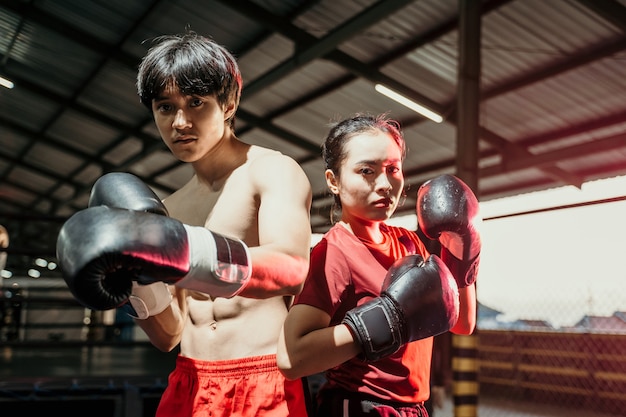 Luchadores femeninos y masculinos parados en guantes de boxeo y posan espalda con espalda en el ring