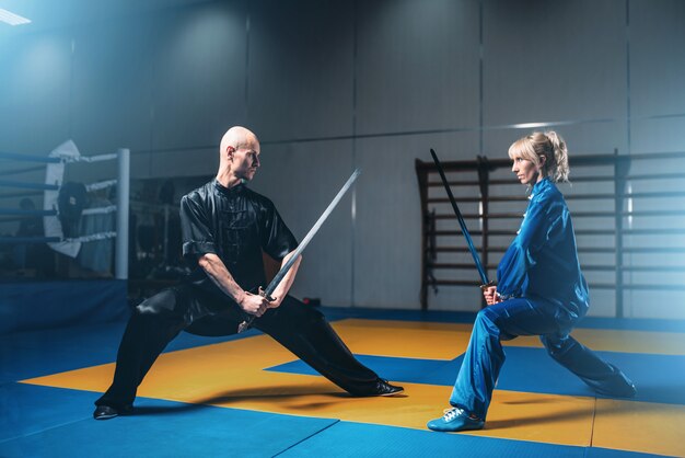 Luchadores de Wushu, hombre y mujer con espadas