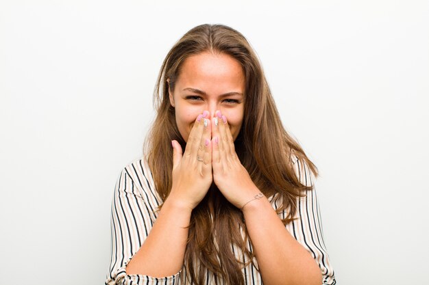 luciendo feliz, alegre, afortunada y sorprendida cubriendo la boca con ambas manos