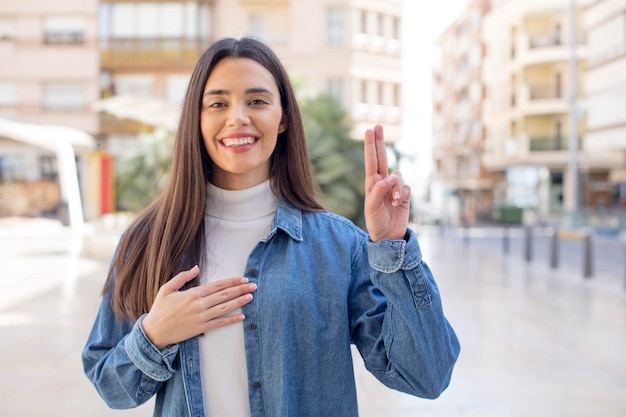 luciendo feliz, confiado y confiable, sonriendo y mostrando el signo de la victoria con una actitud positiva