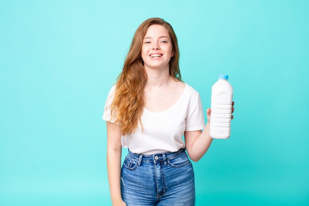 Luciendo feliz y gratamente sorprendido y sosteniendo una botella de leche