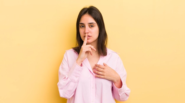 luciendo serio y enfadado con el dedo presionado en los labios exigiendo silencio o silencio manteniendo un secreto