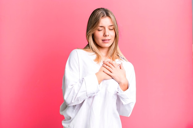 Luciendo triste, herido y con el corazón roto sosteniendo ambas manos cerca del corazón llorando y sintiéndose deprimido