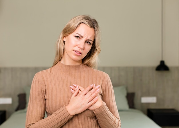 Luciendo triste, herido y con el corazón roto sosteniendo ambas manos cerca del corazón llorando y sintiéndose deprimido